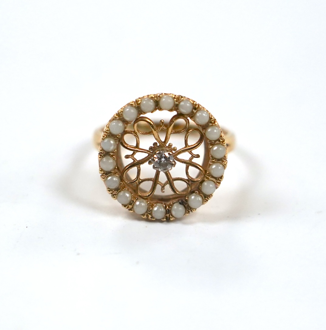 A pierced 14k yellow metal, seed pearl and diamond cluster set circular ring, size P/Q, gross weight 5.2 grams.